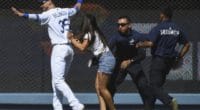 Los Angeles Dodgers right fielder Cody Bellinger is rushed by a fan on the field at Dodger Stadium