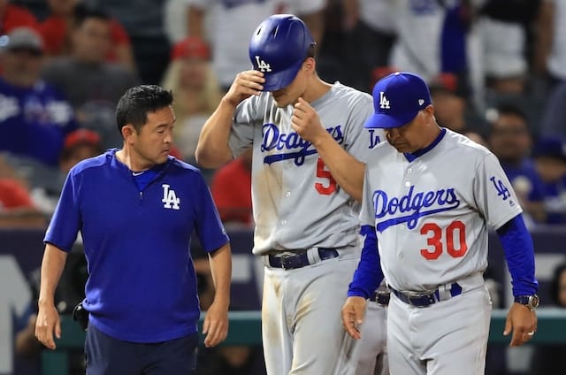 Los Angeles Dodgers manager Dave Roberts and a team trainer walk off the field with Corey Seager after his hamstring injury