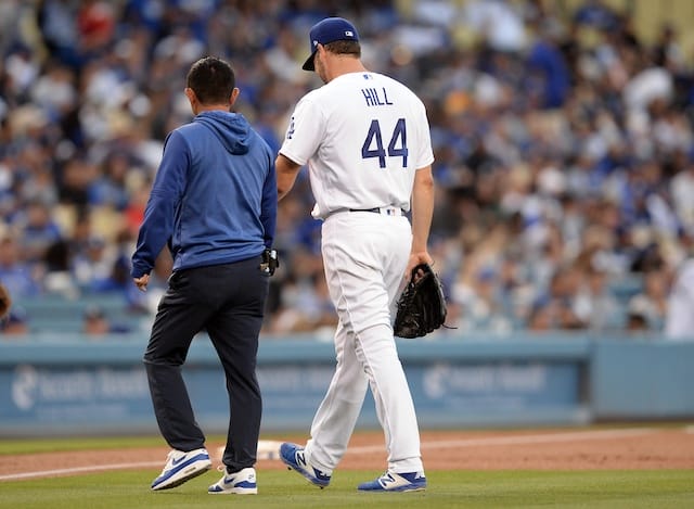 Starting pitcher Rich Hill walks off the field with a Los Angeles Dodgers trainer