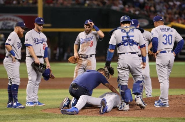 Los Angeles Dodgers manager Dave Roberts, a trainer and teammates David Freese, Russell Martin, Chris Taylor and Justin Turner stand around Dustin May after he is hit by a line drive